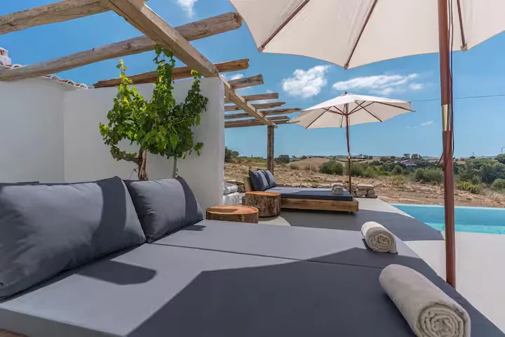 Off-season poolside retreat with empty daybeds and umbrellas at a quiet Mediterranean villa overlooking rolling hills.