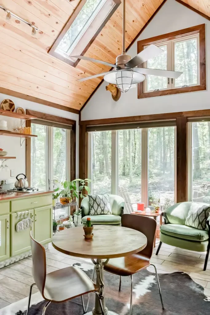 Cozy off-season forest cabin interior with vaulted wood ceiling, skylights, green armchairs and tranquil natural light