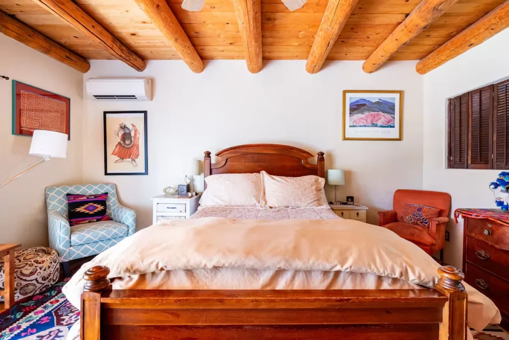 Quiet adobe-style bedroom with rustic wooden beams, southwest textiles and plush bedding in a serene off-season retreat.
