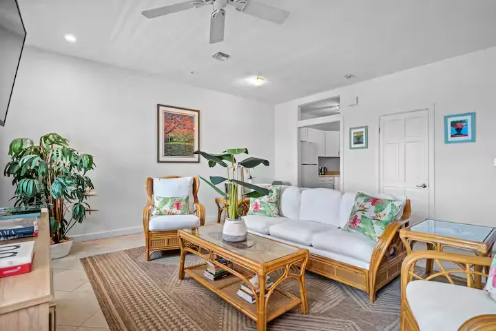 Cozy vacation rental living room off-season with bright rattan furniture, tropical cushions and relaxing island vibe