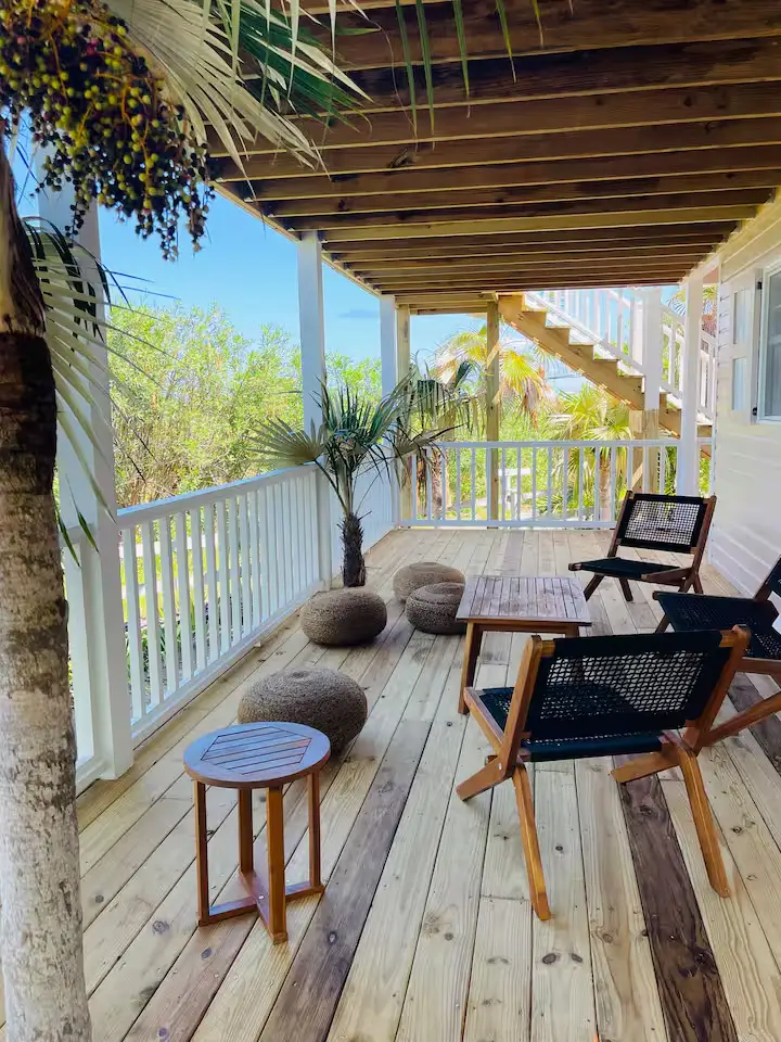 Quiet wooden beach house veranda with lounge chairs and palm trees, a serene off-season tropical retreat