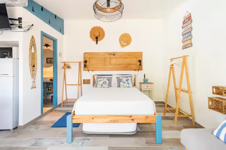 Minimal coastal vacation rental bedroom with surfboard, sun hats and empty off-season retreat ambiance