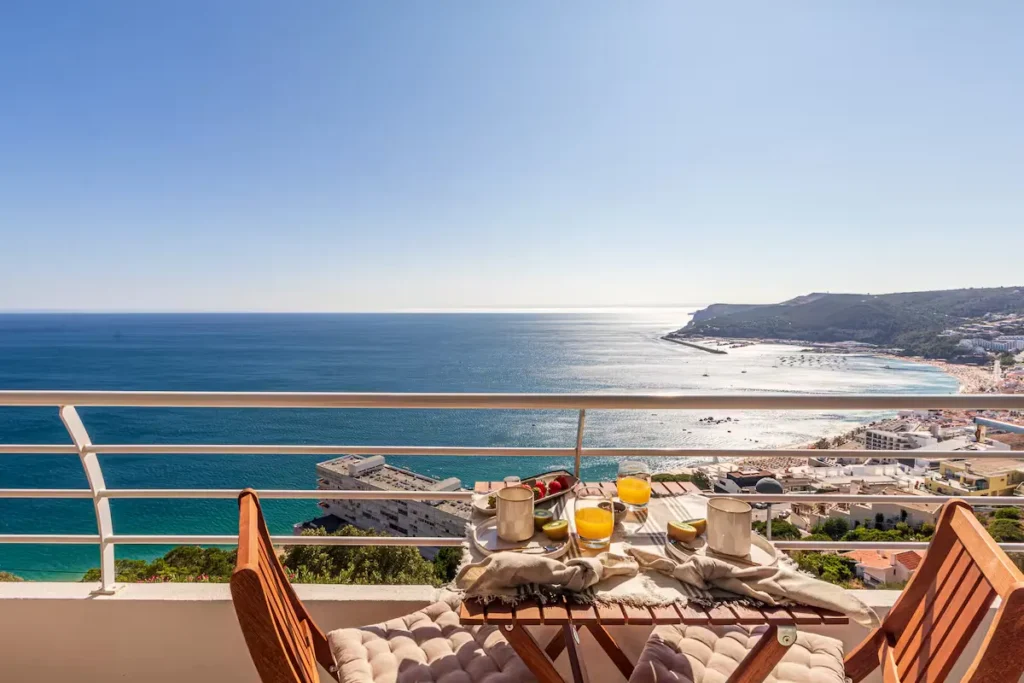 Balcony breakfast with coffee and juice overlooking a calm blue sea and nearly empty beach in off-season