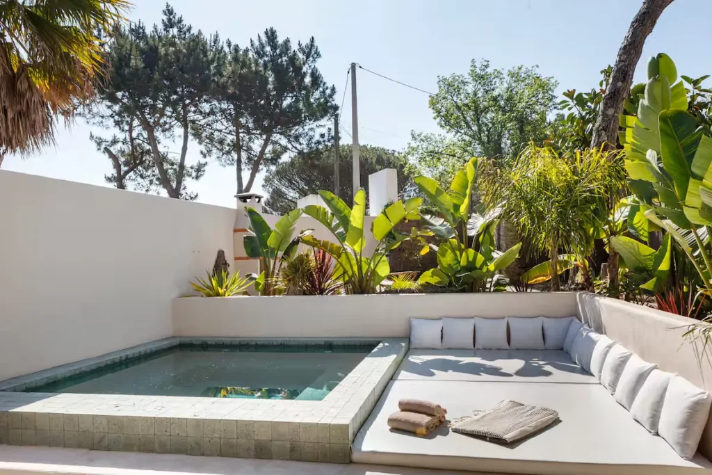Empty private plunge pool and cushioned lounge area surrounded by tropical plants in a quiet off-season courtyard retreat
