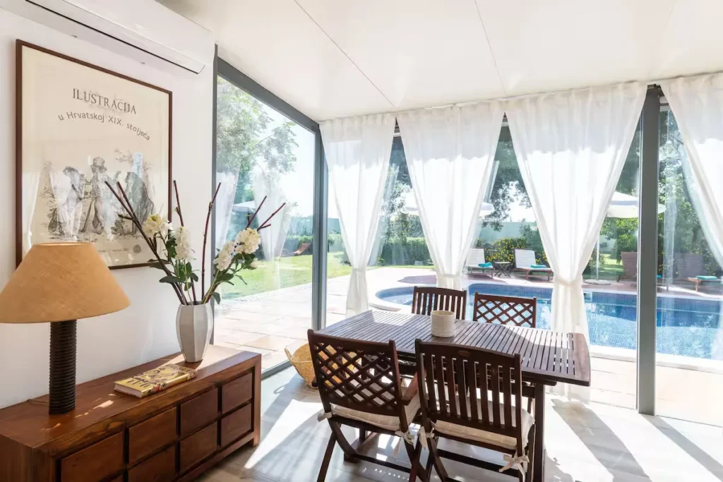 Sunlit travel villa dining area opening to a private pool terrace, showcasing a serene off-season getaway atmosphere.