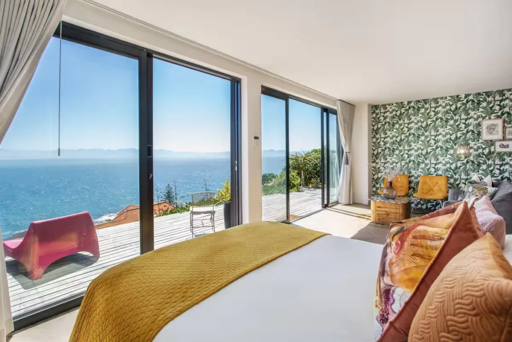 Ocean-view bedroom in a beachfront villa with open terrace doors and empty chairs, reflecting a peaceful off-season stay.