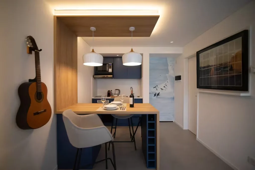 Cozy off-season studio with kitchenette and wooden breakfast bar for two, wine bottle, hanging guitar and ambient lighting