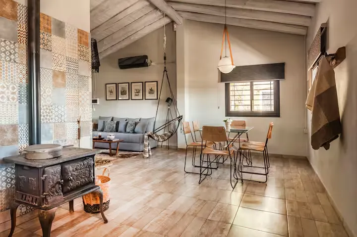 Cozy rustic retreat living room with wood stove, hammock chair and empty dining area, evoking a quiet off-season getaway.