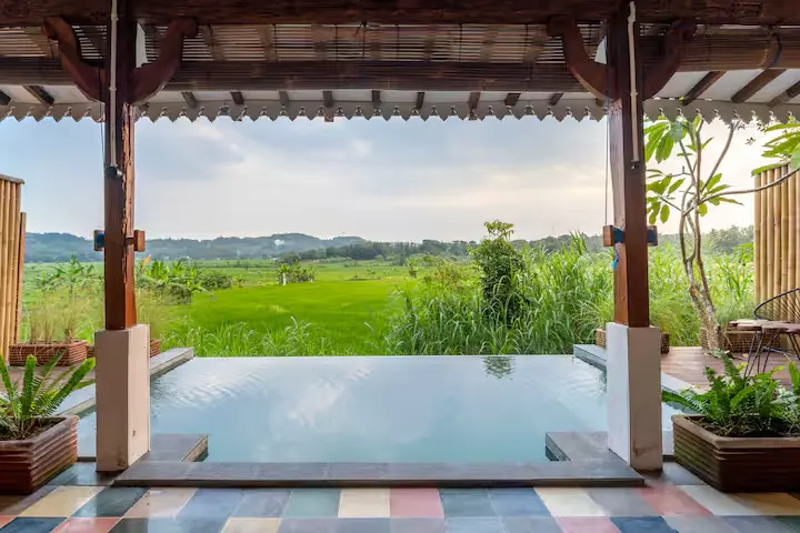 Empty tropical resort terrace with infinity pool and rice field views, offering off-season serenity and lush green retreat