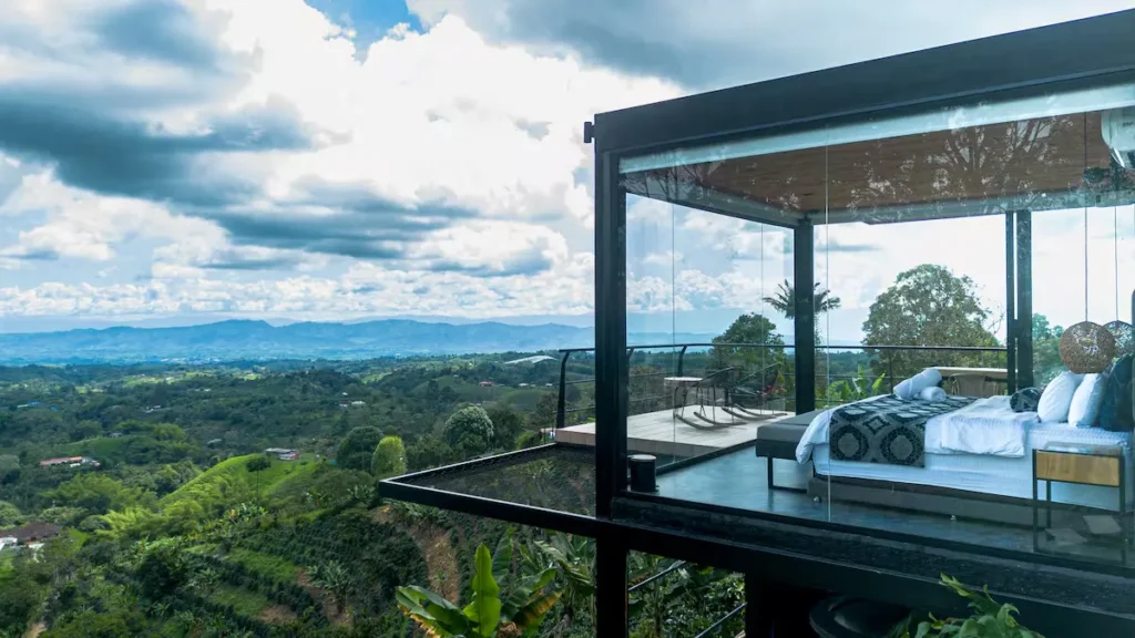 Quiet off-season luxury hillside suite with floor-to-ceiling windows overlooking lush green valley.