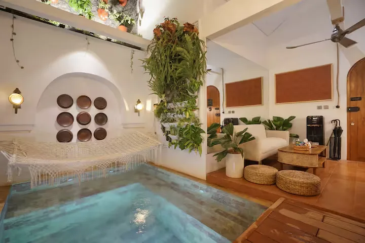 Serene boutique hotel lobby with indoor plunge pool, hammock and lush greenery in a quiet off-season retreat