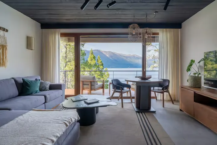 Cozy lakeside retreat living room with mountain lake view and empty balcony in off-season, a serene travel escape.
