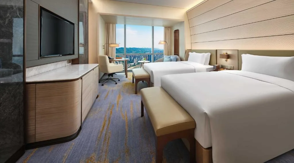 Spacious modern hotel room with two beds and empty city skyline view, ideal quiet off-season stay