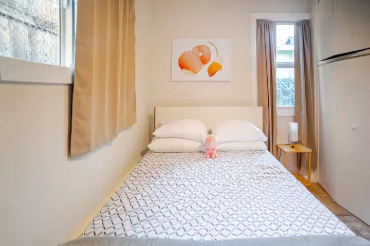 Cozy minimalist guest room with double bed, plush toy and soft curtains in a quiet off-season vacation rental.