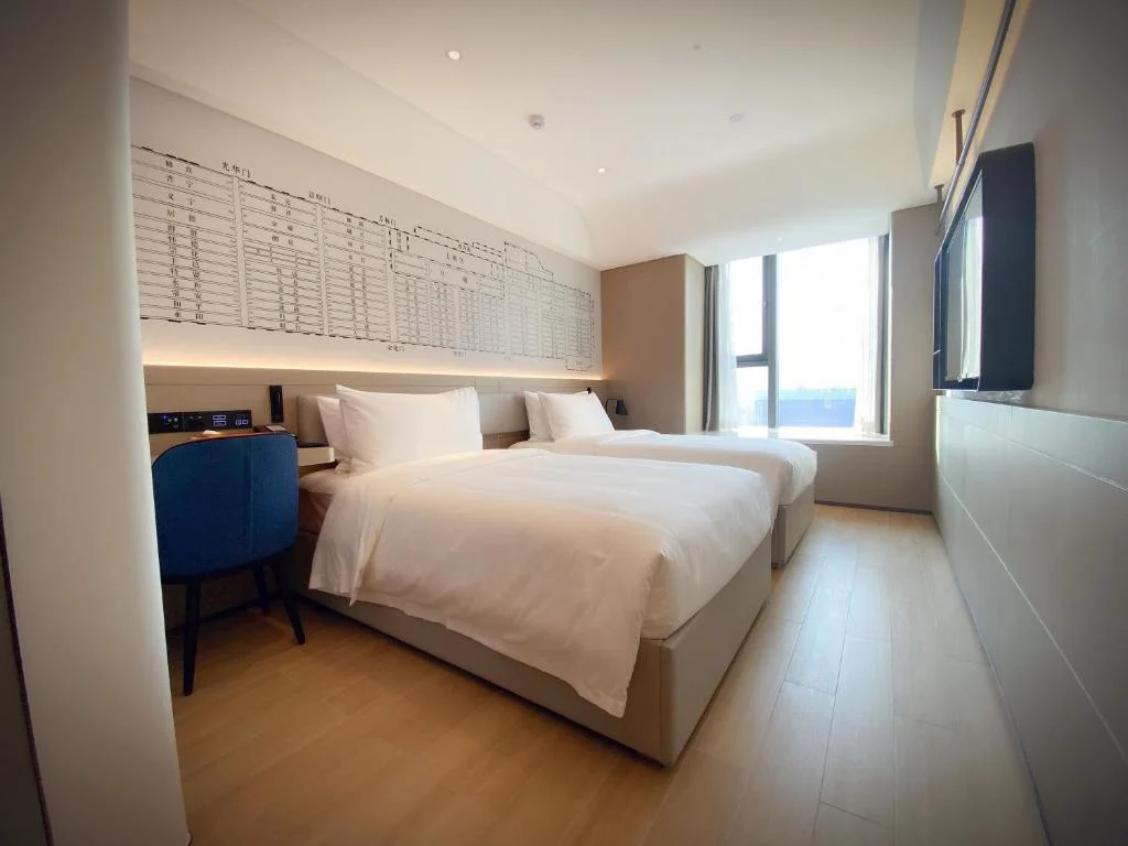 Empty modern hotel room with twin beds and desk by a sunlit window, showcasing off-season calm and serene travel stay