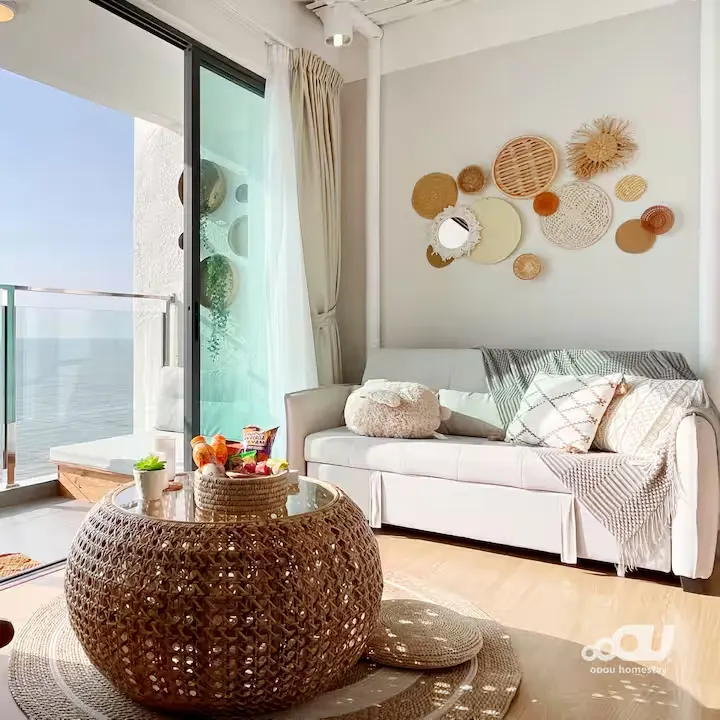 Bright coastal apartment living room with woven coffee table, sea-view balcony and off-season calm.