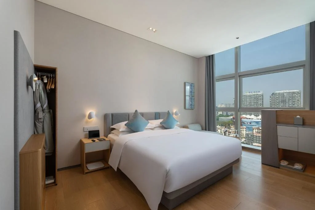 Modern hotel room with king bed and city skyline view, perfect for a quiet off-season urban travel stay.