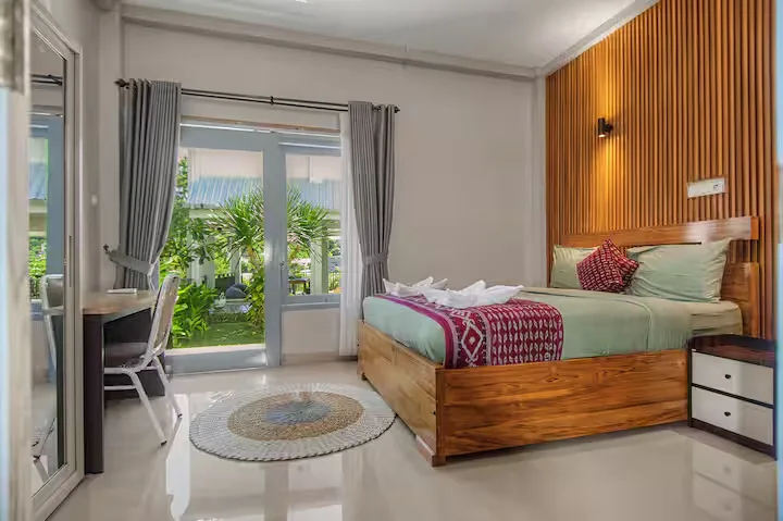 Bright tropical resort bedroom with wooden accents opening to lush garden, serene off-season retreat atmosphere