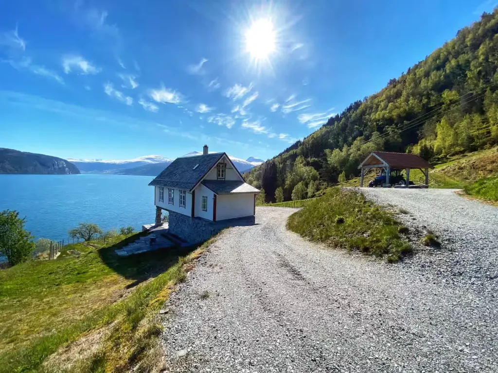 Sunlit off-season lakeside retreat on gravel path by a serene mountain lake under clear blue sky, peaceful and secluded