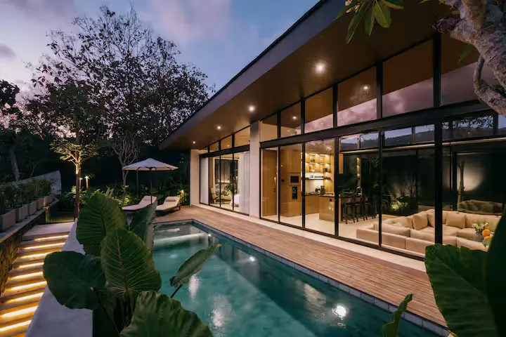 Serene off-season luxury villa at dusk with illuminated private pool, modern glass walls and quiet tropical garden retreat.