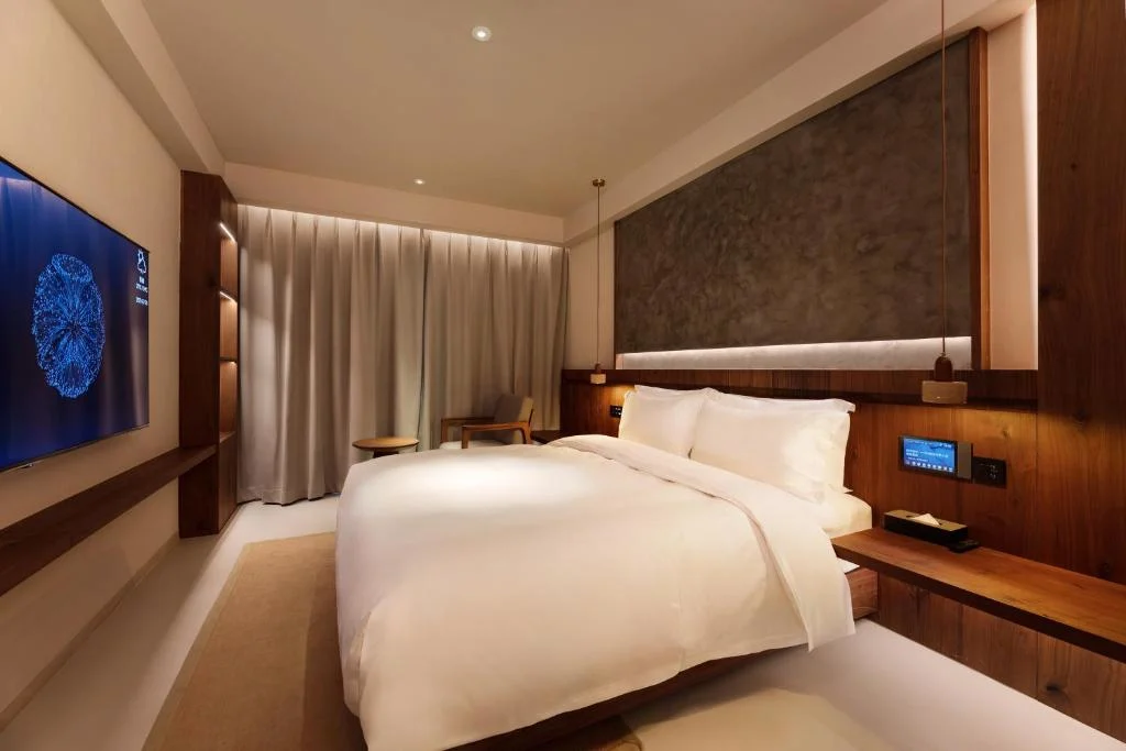 Cozy empty hotel bedroom with warm wood accents, king bed and ambient lighting, perfect for off-season travel escape.