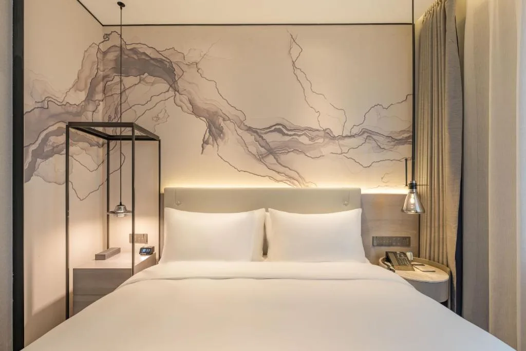 Minimalist modern hotel room with crisp white bedding and ambient lighting, offering a quiet off-season travel retreat.