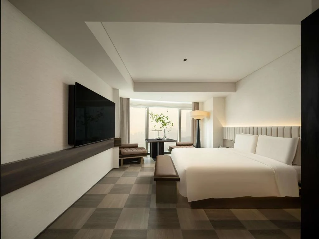 Spacious modern hotel room with king bed, minimalist décor and city-view window offering a quiet, off-season retreat.