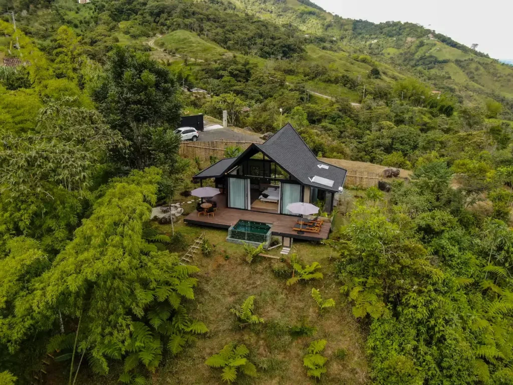 Hillside cabin retreat with empty terrace, umbrellas and plunge pool overlooking lush mountains in off-season calm
