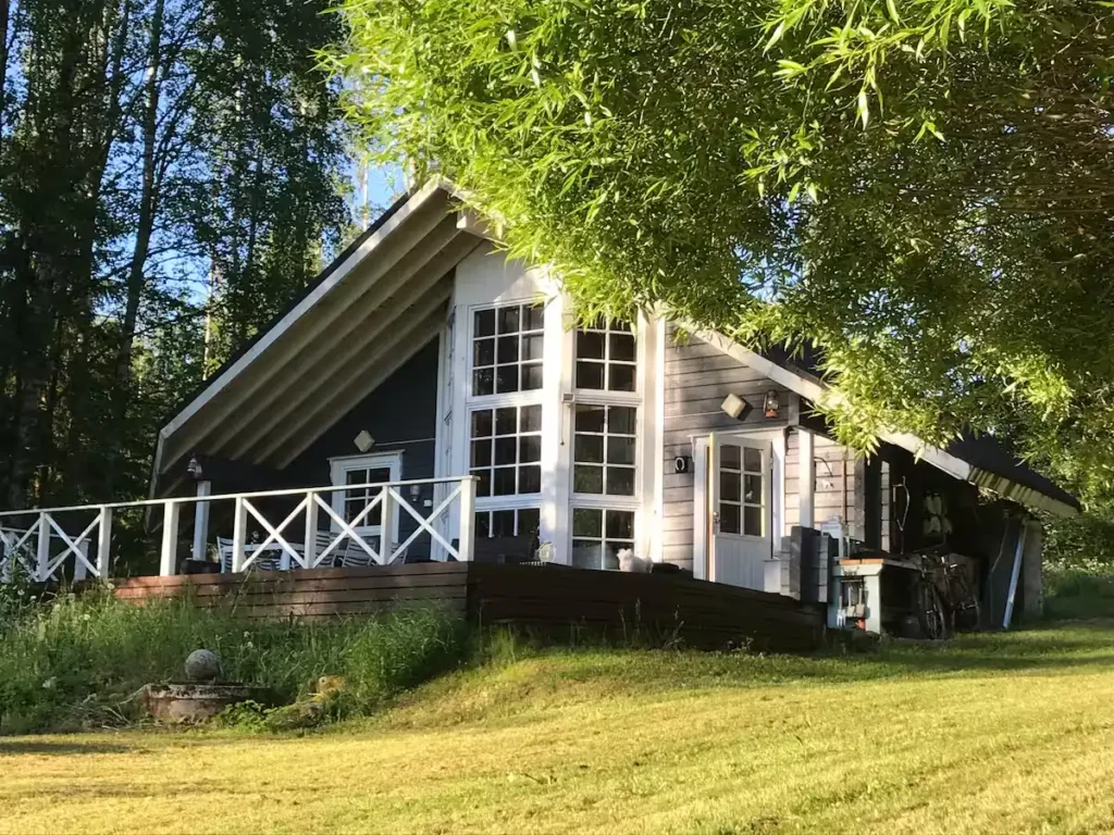 Rustic forest cabin with empty deck and overgrown lawn in serene off-season travel retreat under soft sunlight