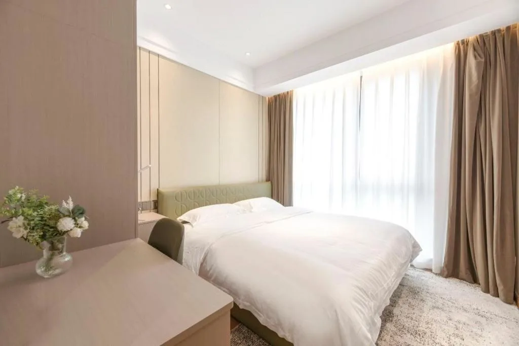 Minimalist hotel room with king bed, soft white linens and fresh flowers, offering a quiet off-season retreat.