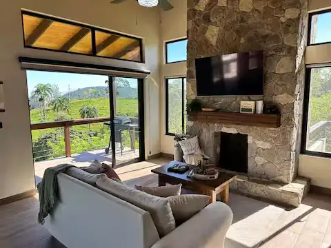 Off-season mountain retreat living room with stone fireplace, cozy sofa, coffee table and quiet valley views through windows.