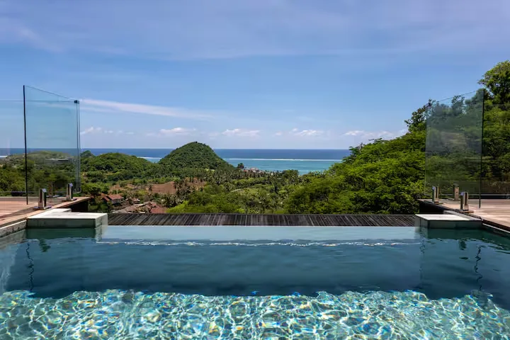 Secluded tropical infinity pool overlooking lush green hills and turquoise sea on a peaceful off-season getaway