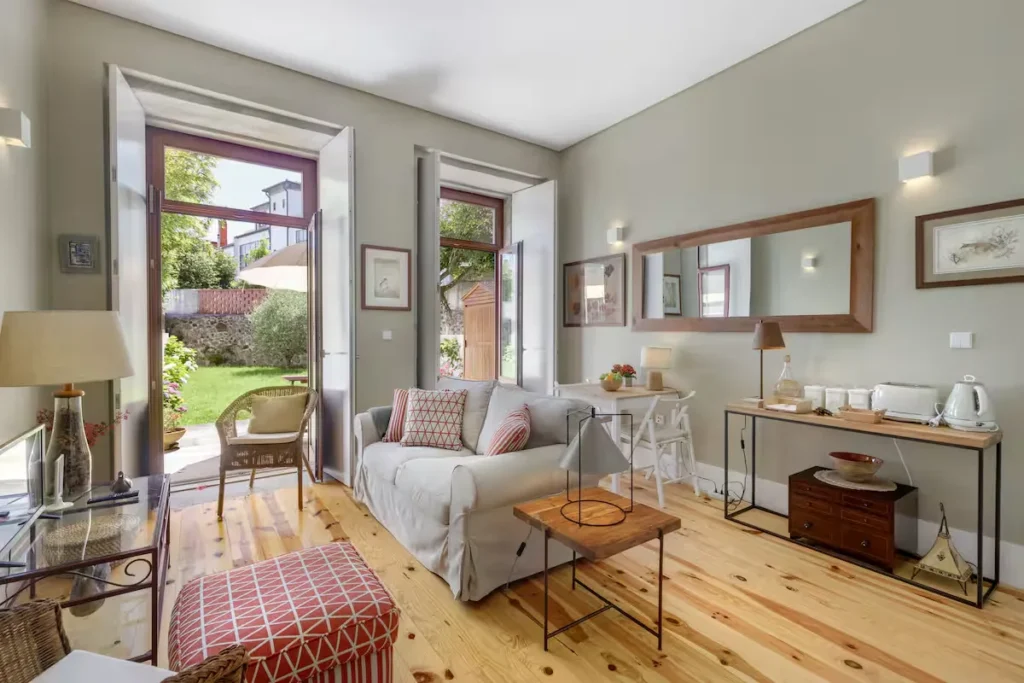 Cozy vacation rental living room with open patio doors to a green garden, offering quiet off-season charm and seclusion.