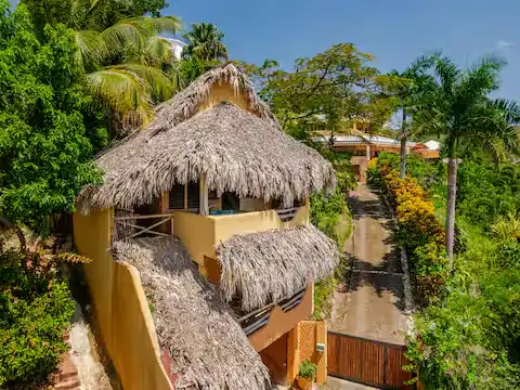 A secluded two-story tropical villa with thatched roofs, lush palms and empty paths in a quiet off-season getaway setting