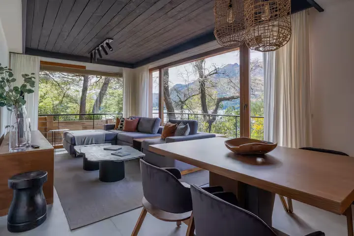 Cozy modern lakeside travel retreat interior with large windows overlooking bare trees and misty lake in off-season calm.