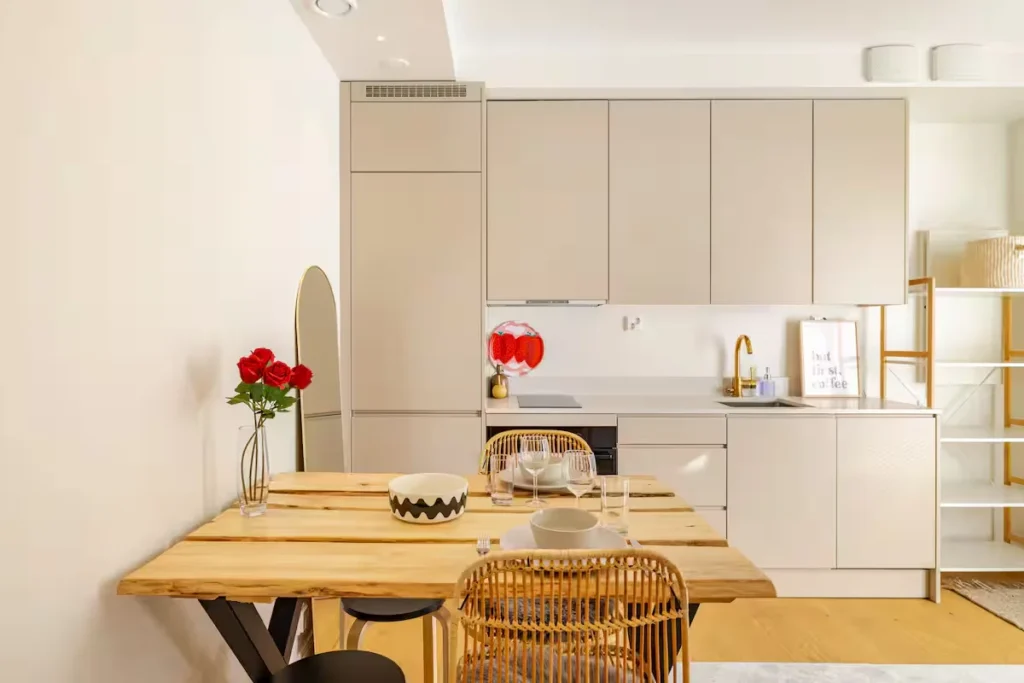 Cozy holiday rental kitchen with wooden dining table set for two, off-season tranquility in a bright vacation apartment.