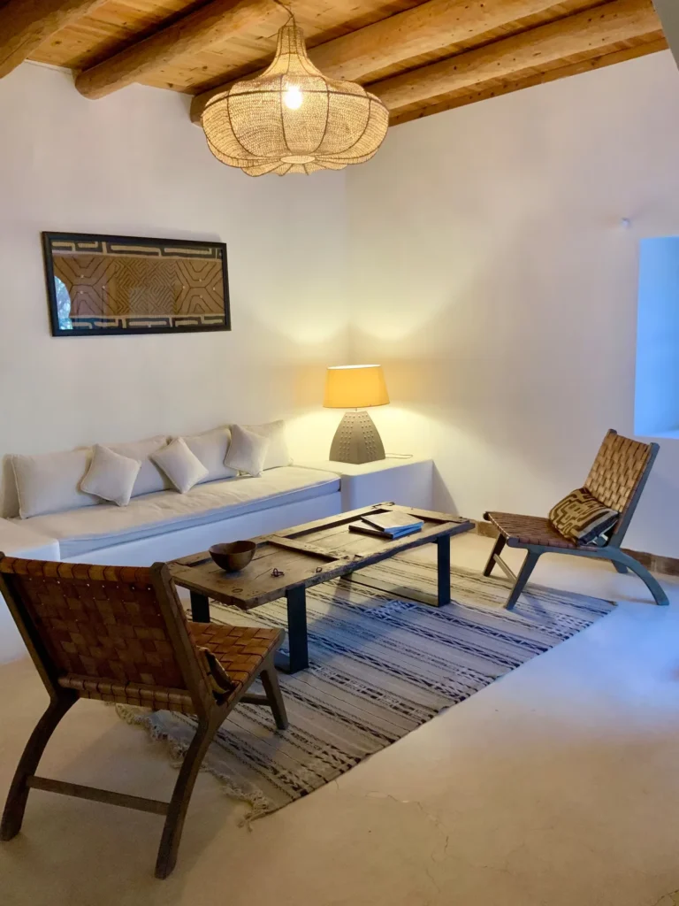 Cozy boho-chic villa living room with whitewashed walls, wooden beams and minimal decor, ideal off-season travel getaway.