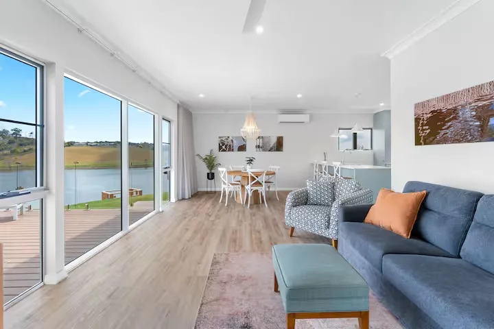 Bright modern lakeside vacation rental with panoramic windows opening to a serene off-season waterfront and empty deck