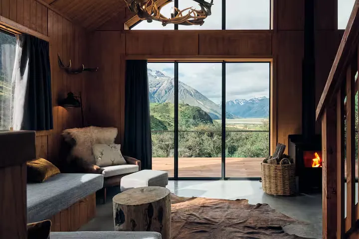 Cozy off-season mountain cabin with wood stove, antler chandelier and sliding doors framing misty peaks and valley view