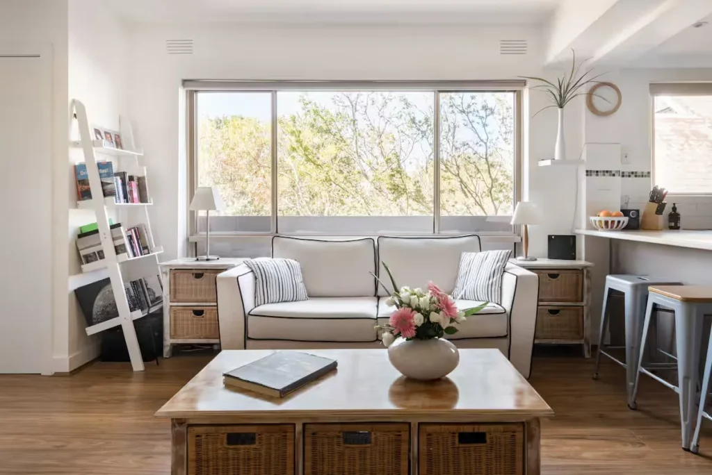 Cozy off-season vacation rental living room with bright natural light, neutral décor, wooden floors and a welcoming sofa.