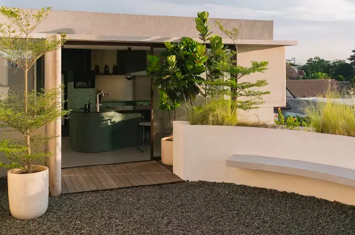 Empty rooftop terrace and open-air bar in a boutique villa, quiet off-season ambiance with potted trees and sunset light.
