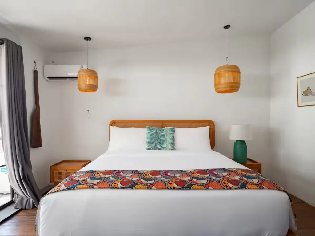 Empty tropical-style guestroom with rattan bed, white linens, and bamboo lamps, tranquil off-season resort retreat