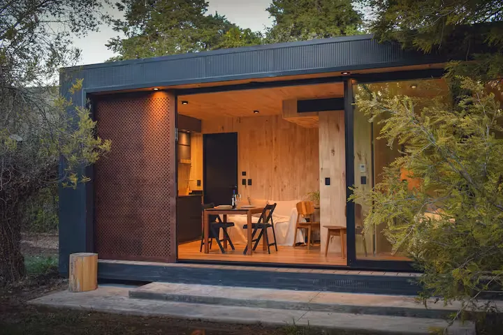 Off-season wooden glamping cabin retreat in quiet forest, warm interior glowing at dusk, perfect cozy getaway.