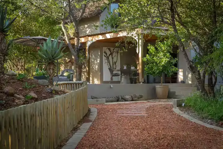 Empty forest lodge patio with lounge chairs, gravel pathway and lush greenery in a tranquil off-season travel retreat.