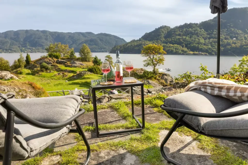 Off-season lakeside retreat with two lounge chairs and rosé wine overlooking a tranquil lake and rolling hills
