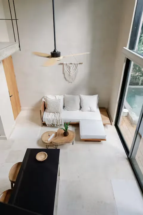 Off-season minimalist villa living area with white sectional sofa, wooden coffee table and serene poolside view (vacation rental calm)
