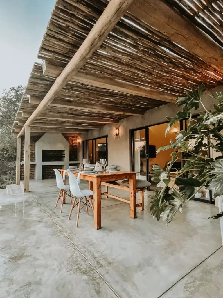 Quiet rustic lodge patio under wooden pergola, set dining table on concrete floor with soft lighting in off-season.
