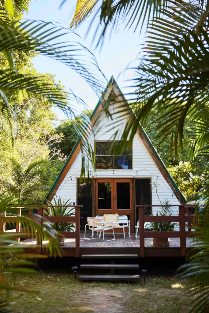 Secluded A-frame cabin deck framed by palm trees in a tranquil off-season tropical retreat.