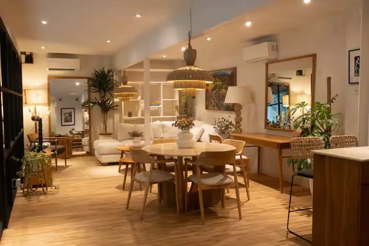 Cozy empty lodge dining area with wicker chairs, pendant lights and potted plants, calm off-season vibe in a rustic retreat.