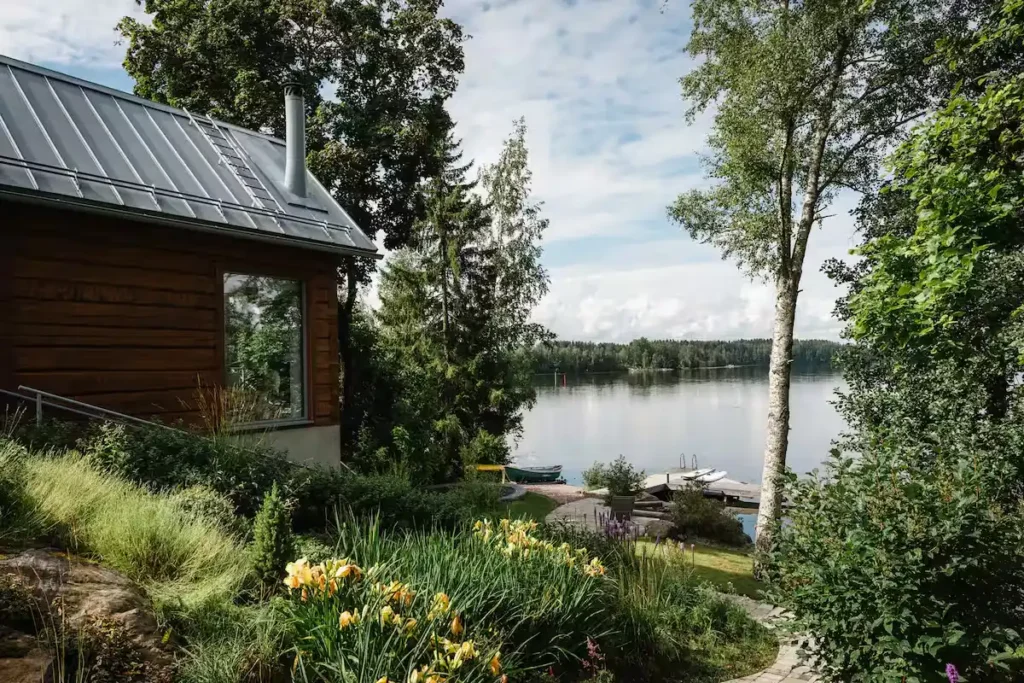 Off-season lakeside cabin retreat with empty dock, yellow flowers and overcast skies offering serene travel escape.